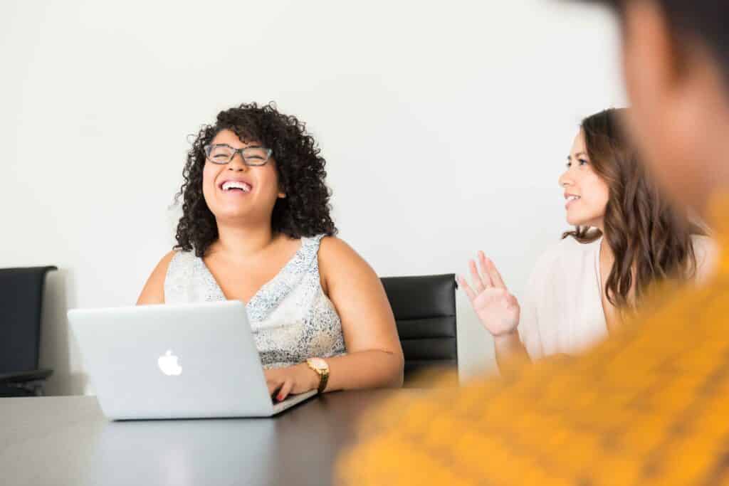 Two women smiling in front of a laptop