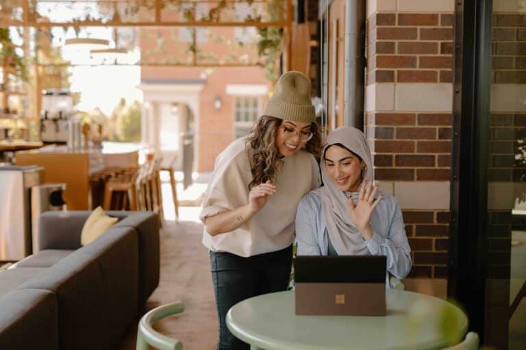 Two women doing a video conference in front of a laptop